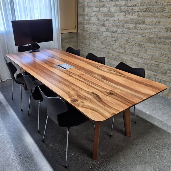 Moderner Konferenzraum mit Holztisch und Stühlen.