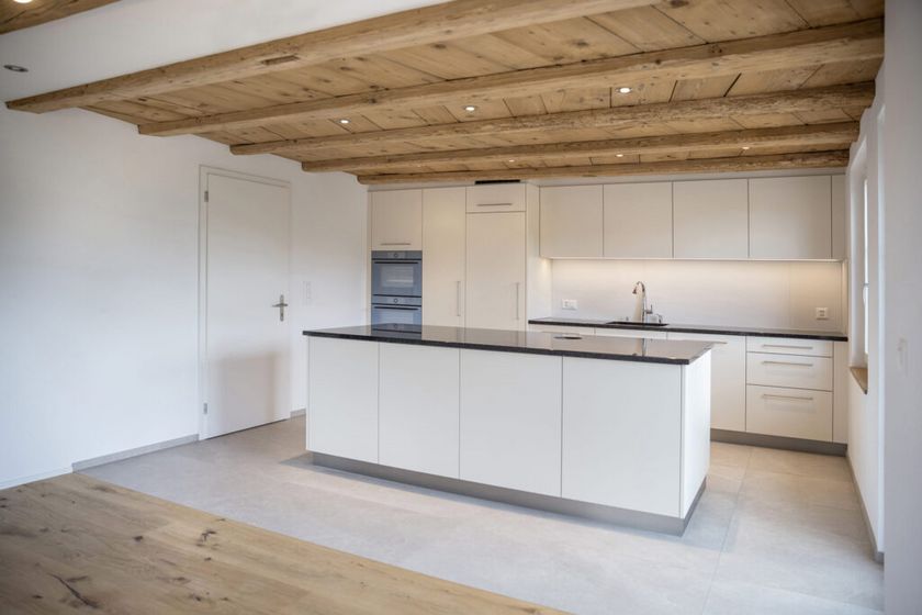 Elegante moderne Küche mit Holzdecke und hellen Einbauschränken.