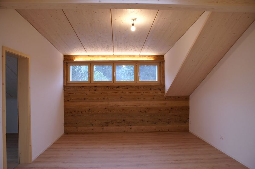 Holzverkleideter Innenraum mit Fenstern und moderner Decke.