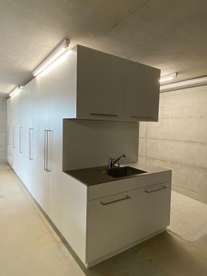 Moderne weisse Küchenzeile mit Spüle in minimalistischem Raum.