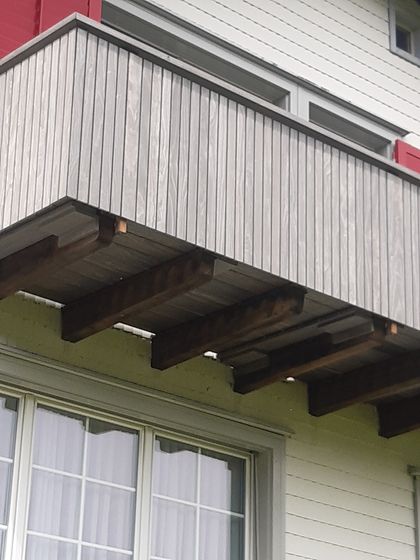 Holzbalkon mit modernen Vertäfelungen an einem Gebäude.
