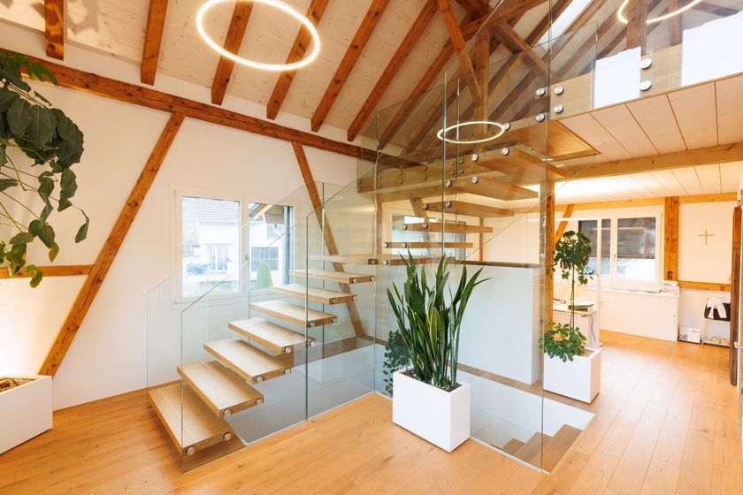 Modernes Interieur mit Holztreppe und Glasgeländer in einem stilvollen Raum.