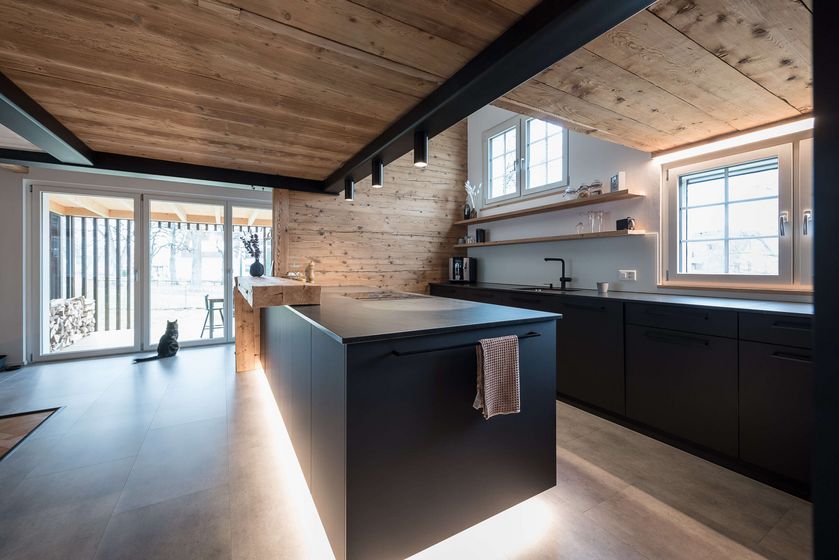 Moderne Küche mit Holzelementen und grossen Fensterfronten.