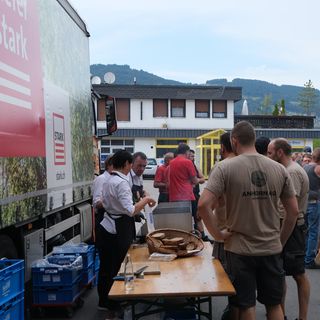 Mitarbeiter von Stark AG versammeln sich um einen Tisch bei einem Firmenevent im Freien.