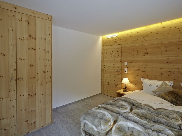 Gemütliches Schlafzimmer mit Holzverkleidung und gedämpfter Beleuchtung.