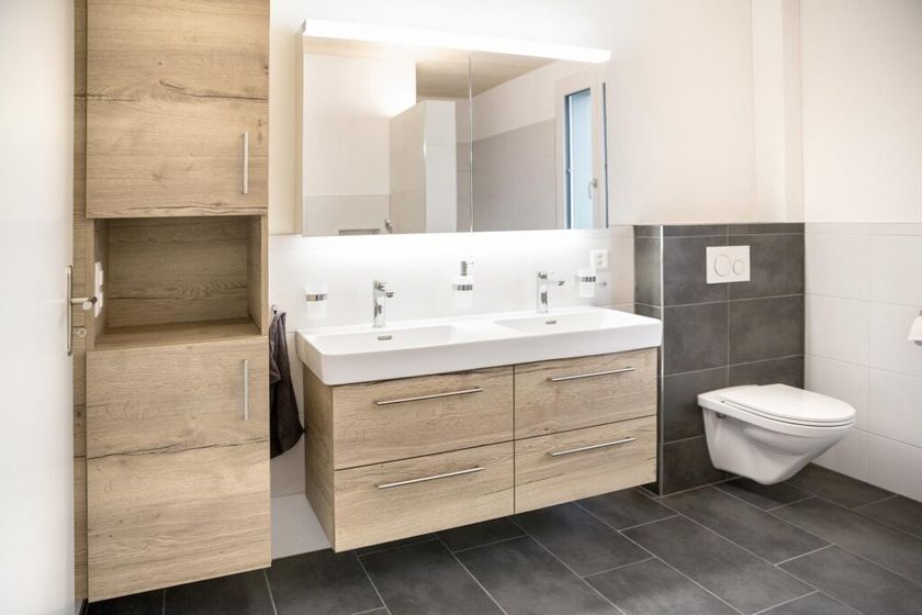 Modernes Badezimmer mit Holzschrank und Doppelwaschbecken.