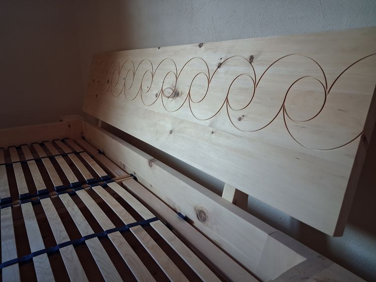 Holzlattenrost und Kopfteil mit Spiralmuster.