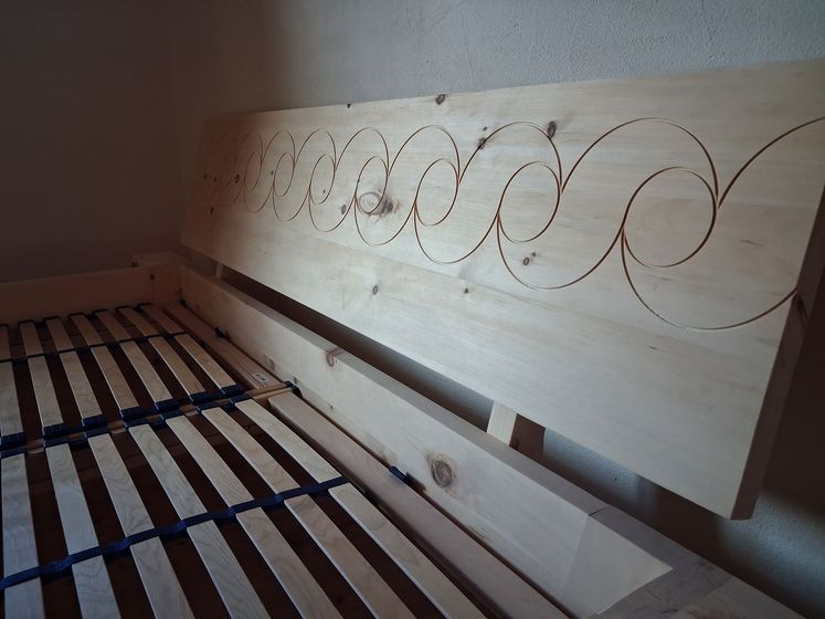 Holzlattenrost und Kopfteil mit Spiralmuster.