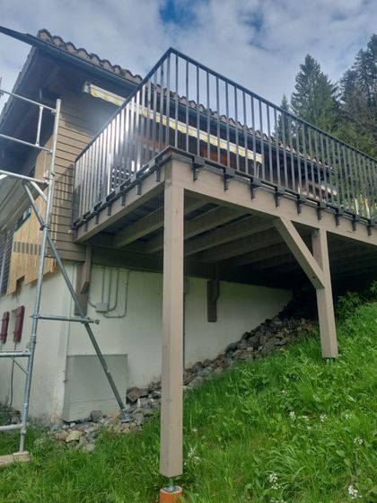Erhöhte Holzterrasse mit Metallgeländer und Blick auf Wald