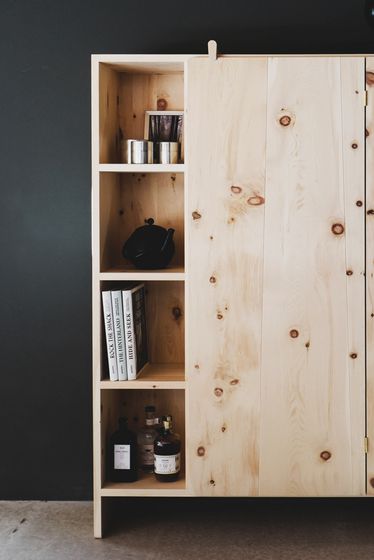 Holzschrank mit Regalfächern, dekoriert mit Büchern und Flaschen.