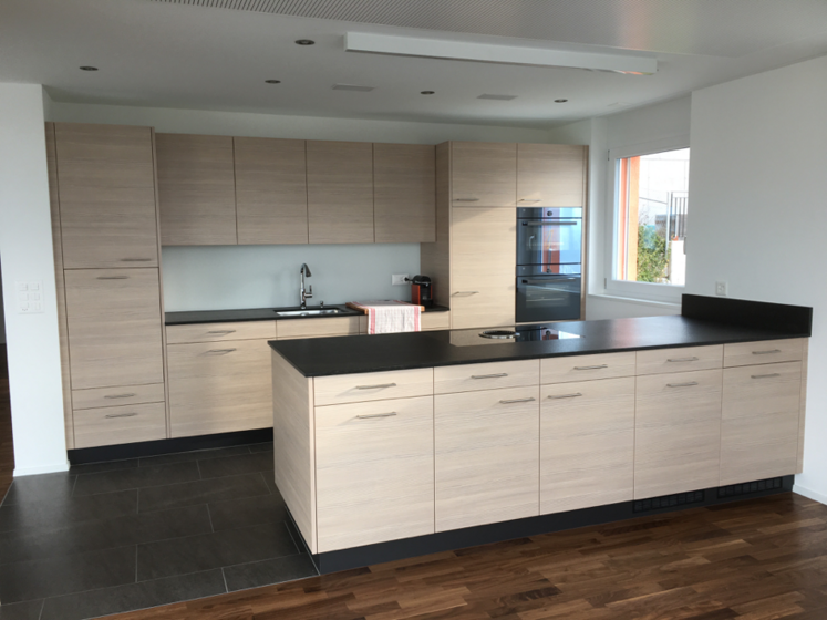 Moderne Küche mit Holzschränken und schwarzen Arbeitsplatten.