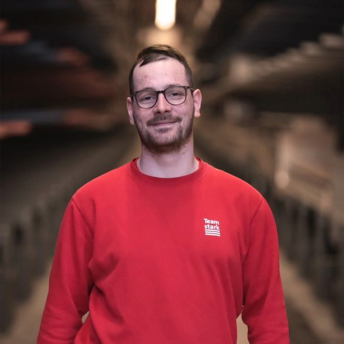 Mitarbeiter der Stark AG in einem roten Pullover steht in einem Lagerhaus.