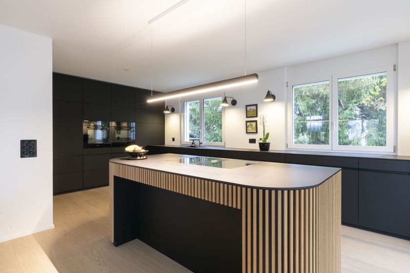 Moderne Küche mit Holzakzenten und schwarzen Möbeln.