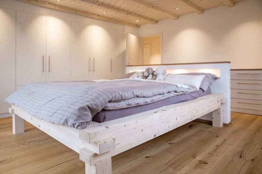 Gemütliches Schlafzimmer mit Holzbett und moderner Einrichtung.