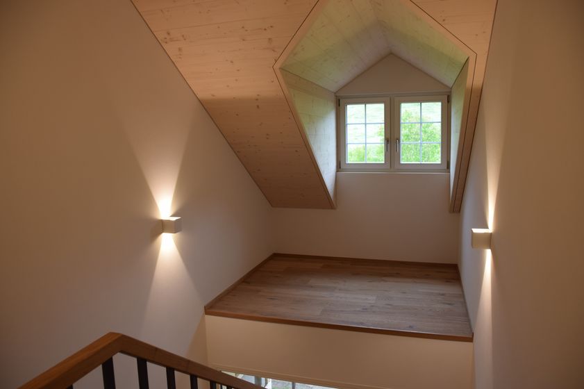 Modern gestalteter Dachboden mit Holzboden und Dachfenster in einem Lichtdurchfluteten Raum.