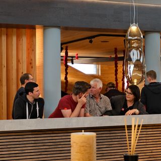 Personengruppe bei Diskussion in modernem Innenausbau-Showroom mit Holzelementen.
