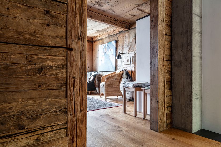 Gemütlicher Raum mit Holzwänden und Parkettboden, dekoriert mit geflochtenen Sesseln und Kunst an der Wand.
