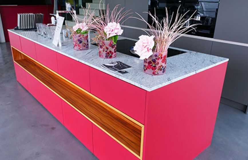 Moderne pinke Kücheninsel mit Marmorplatte und Blumendekoration.