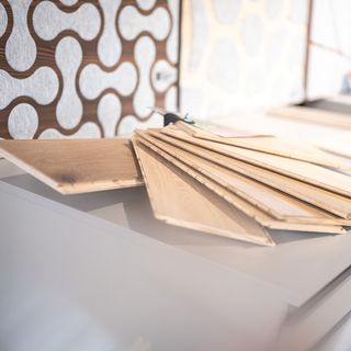 Holzpaneele auf einem Tisch mit dekorativem Wandbelag im Hintergrund.