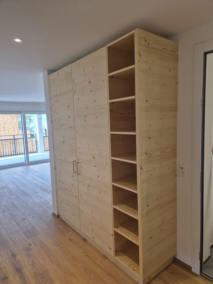 Ein massgefertigter Holzschrank mit offenen Regalen in einem modernen Innenraum.