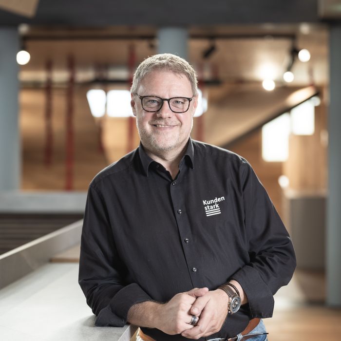 Holzwerkstoff-Experte Stark AG Mann in Holzwerkstoff-Ausstellungshalle mit schwarzem Hemd.
