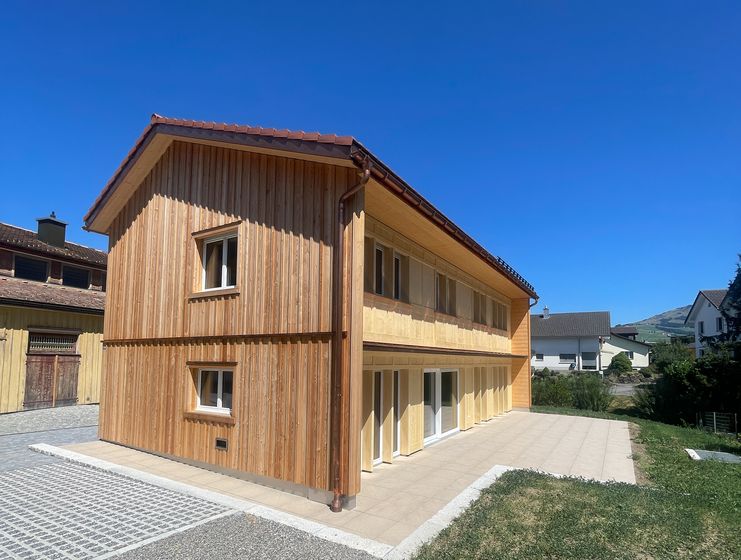 Modernes zweistöckiges Holzgebäude bei sonnigem Wetter.