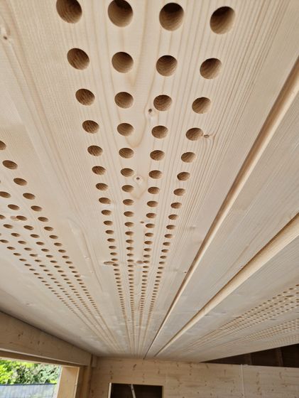 Akustische Holzdecke mit präzisen Bohrlöchern für optimierte Schallabsorption.