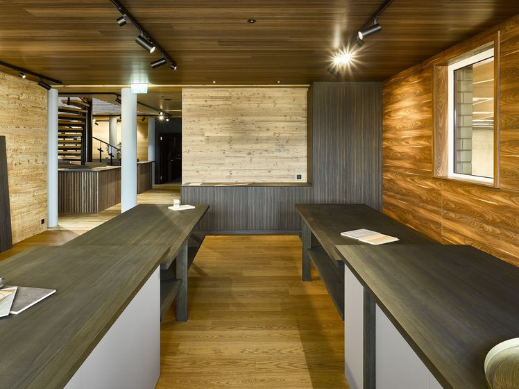 Modernes Interieur mit Holzverkleidungen und Holztischen in einer Ausstellungshalle.