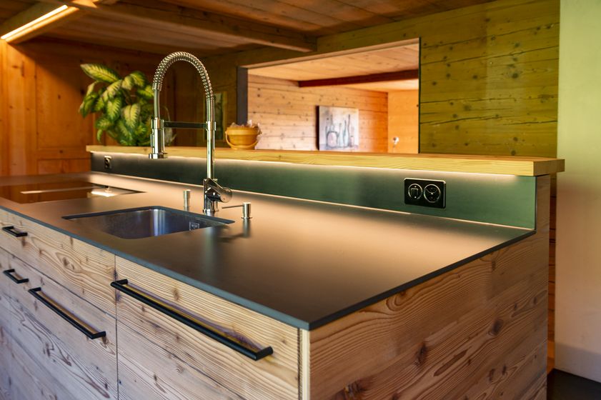 Moderne Küchenzeile aus Holz mit Edelstahlarmaturen und Steckdosen.
