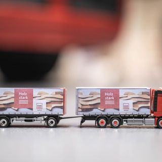 Modell eines roten Lastwagens mit Anhänger und der Aufschrift 'Holz stark' auf stark.ch.