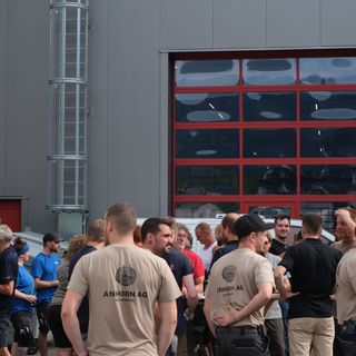 Menschenmenge vor einem Gebäude mit roten Fenstern bei Stark AG.