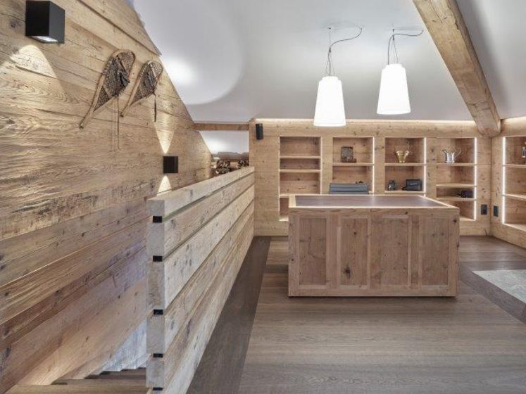 Modernes Interieur mit Holzwänden und -möbeln, beleuchtet durch Hängeleuchten in einem Showroom.