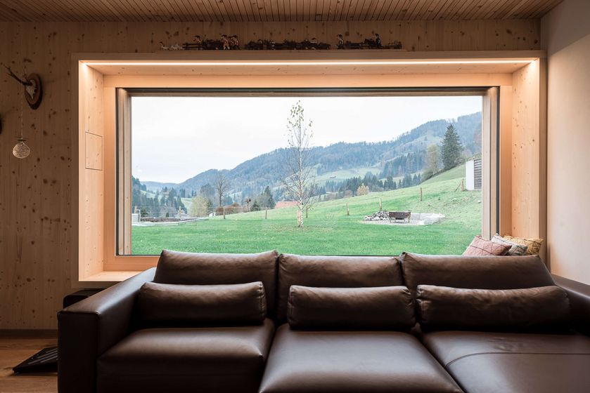 Moderne Holzwandverkleidung mit grossem Fenster und Landschaftsblick.