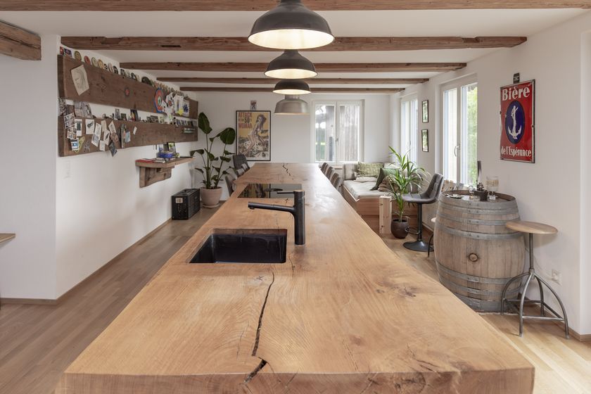 Modern eingerichteter Wohnbereich mit Holzelementen und grossem Tisch.