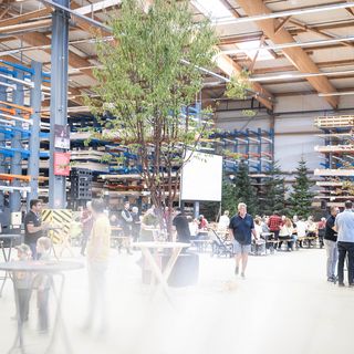 Menschen bei einer Veranstaltung in einer grossen Holzlagerhalle.