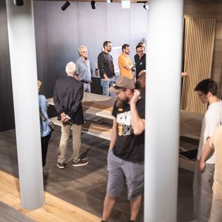 Menschen bei einer Präsentation von Holzwerkstoffen in einem Ausstellungsraum.