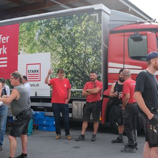 Mitarbeiter der Stark AG stehen entspannt vor einem bunt bedruckten LKW.
