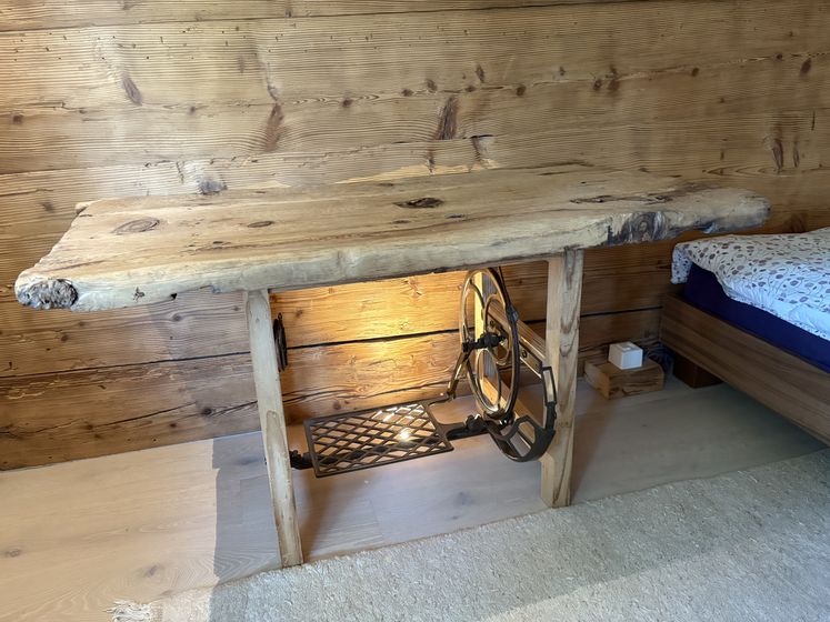 Rustikaler Holztisch mit Pedalgestein an einer Holzverkleidungswand in einem gemütlichen Innenraum.