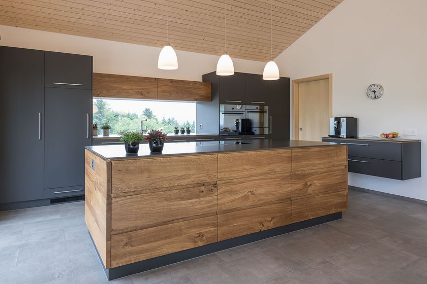 Moderne Küche mit Holz- und Grautönen, ausgestattet mit hängenden Lampen und Pflanzen.