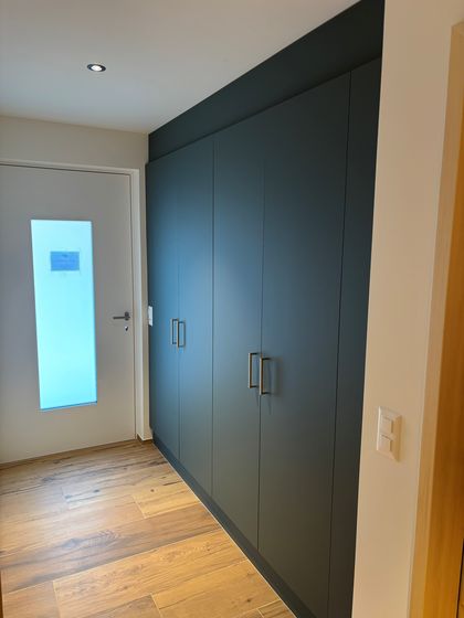 Moderner Eingangsbereich mit Holzfussboden und dunkler Schrankwand.
