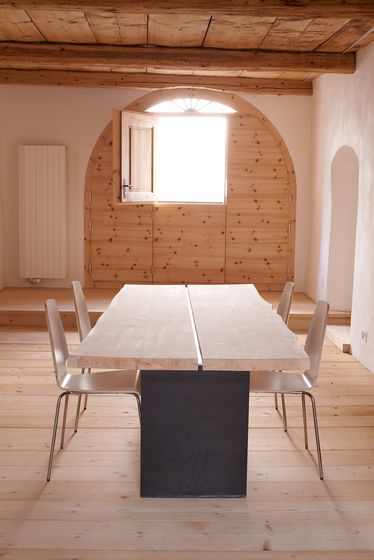 Moderner Holztisch mit vier Stühlen in einem lichtdurchfluteten Raum mit Holzverkleidung.
