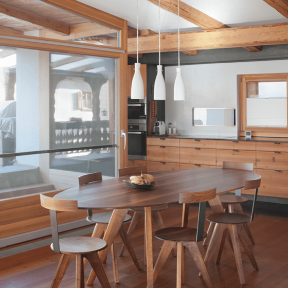 Moderne Küche mit Holzmöbeln und grossen Fenstern.