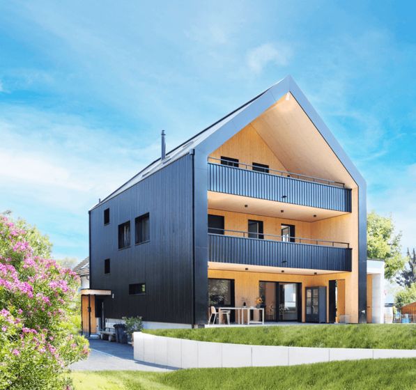 Modernes Holzhaus mit Terrassen und Garten im Sonnenschein.