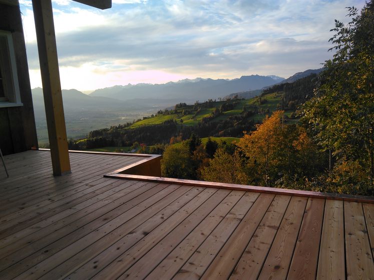 Holzterrasse mit Blick auf eine malerische Berglandschaft im Sonnenuntergang.