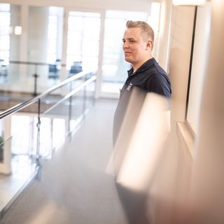 Ein Mitarbeiter steht an einem Geländer in einem modernen Bürogebäude.