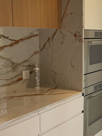 Moderne Küchenarbeitsplatte mit Marmoroptik und Holzschränken.