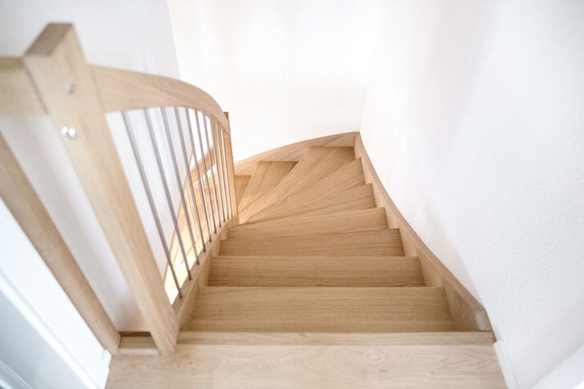 Elegante Holztreppe mit Geländer in hellem Raum.