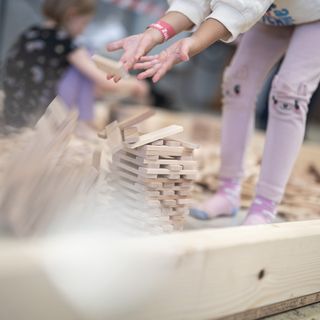 Kind baut mit Holzstücken eine Struktur.