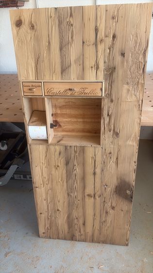 Holzverzierung mit Schrift und Schublade auf rustikaler Holzplatte.