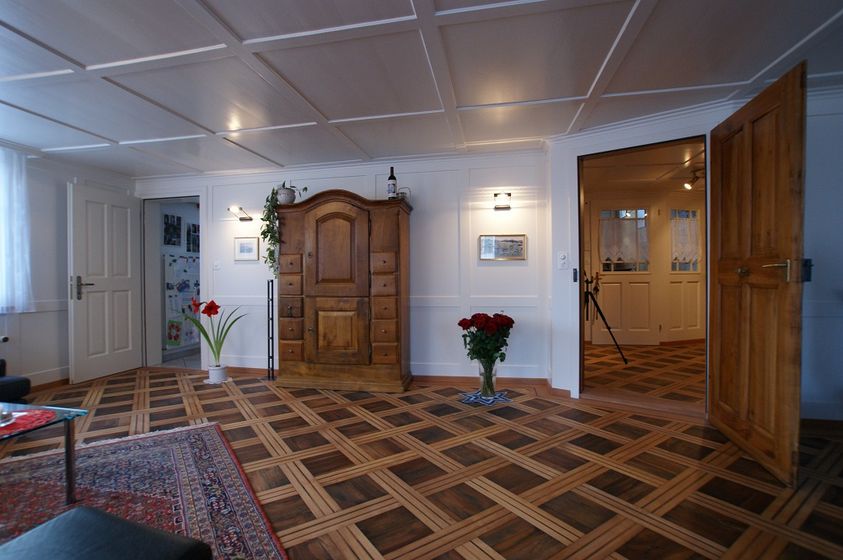 Elegantes Wohnzimmer mit Holzboden und antikem Schrank.
